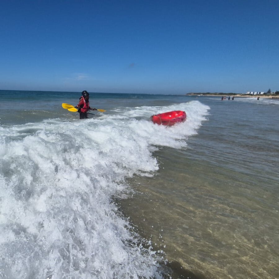Image of person kayaking through a wave in the ocean